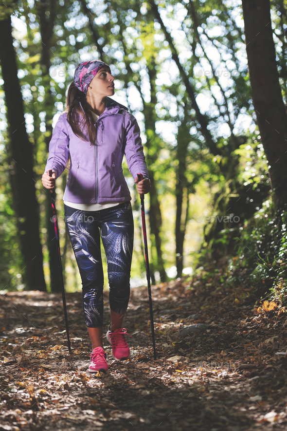 Beautiful girl during an excursion with nordic walking practice in the woods - Stock Photo - Images