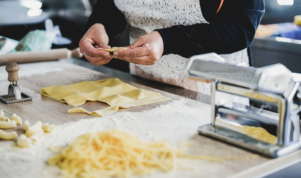 Woman prepare fresh ravioli inside pasta factory - Focus on hands