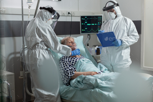 Medical staff in ppe suit helping patient breath with oxygen mask