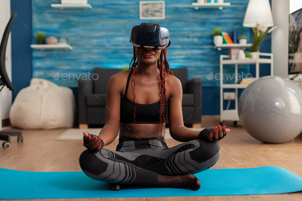 Black woman experiencing virtual reality training body and mind meditating in lotus pose