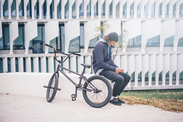 Young man poses with mobile and BMX bike. - Stock Photo - Images