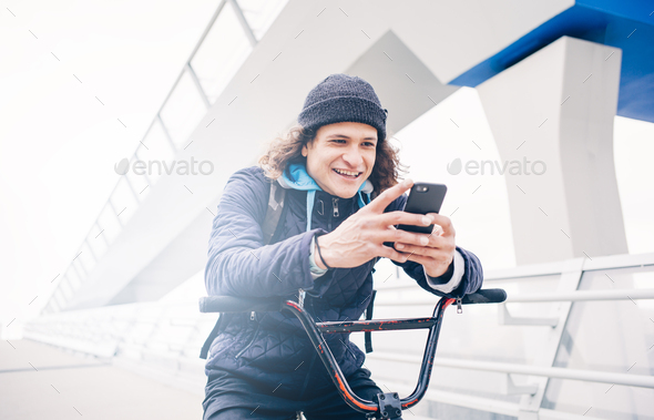 Young man poses with mobile and BMX bike. - Stock Photo - Images
