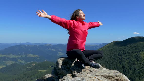 The girl sits on the top of the mountain and meditates. Relax in nature. Happiness and tranquility