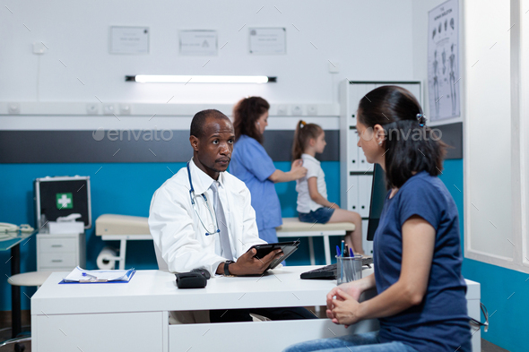 African american pediatrician doctor typing medical symptoms on tablet