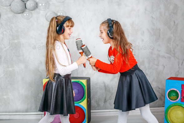 Two little girl friends sing and dance. The concept is childhood - Stock Photo - Images