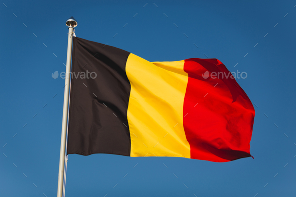 Flag of Belgium on mast. National flag against wind blue sky. Flag of Belgium, capital Bruxelless - Stock Photo - Images
