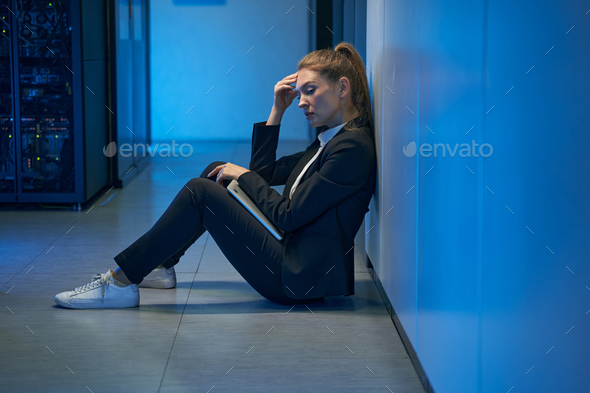 Depressed woman system administrator sitting in hallway