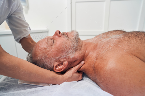 Professional male masseur massages neck and shoulders of young woman in  massage parlor., Stock image