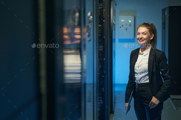 Cute female technician standing in server room
