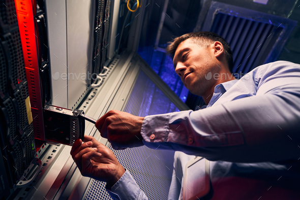 Concentrated engineer adding new HDD to server - Stock Photo - Images
