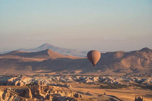 hot air balloon with checkered pattern rising over the Cappadocian valley - Stock Photo - Images