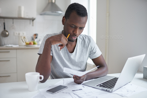 Frustrated man working through paperwork, calculating expenses, trying to save some money
