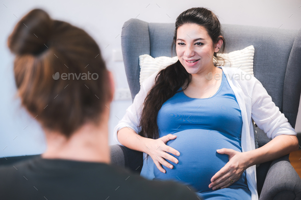 young pregnant woman sitting on bed with loving caring husband trying to connect with baby - Stock Photo - Images