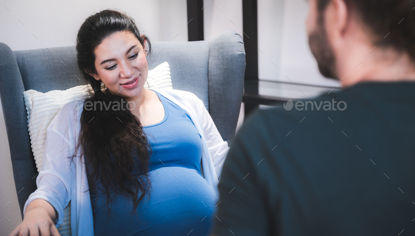 young pregnant woman sitting on bed with loving caring husband trying to connect with baby - Stock Photo - Images