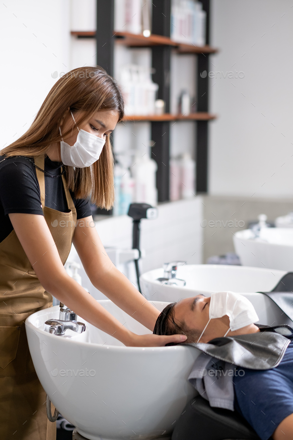 Asian beauty salon barber girl with hygiene mask wash man hair in workplace  Stock Photo by nrradmin