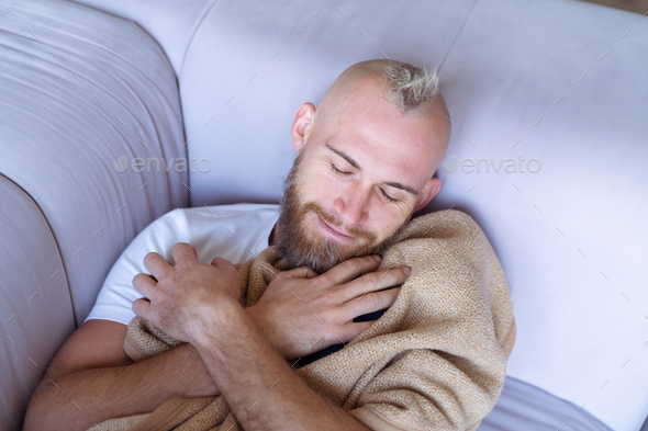 Young man at home on the couch comes off with a cozy warm blanket on a cold winter evening