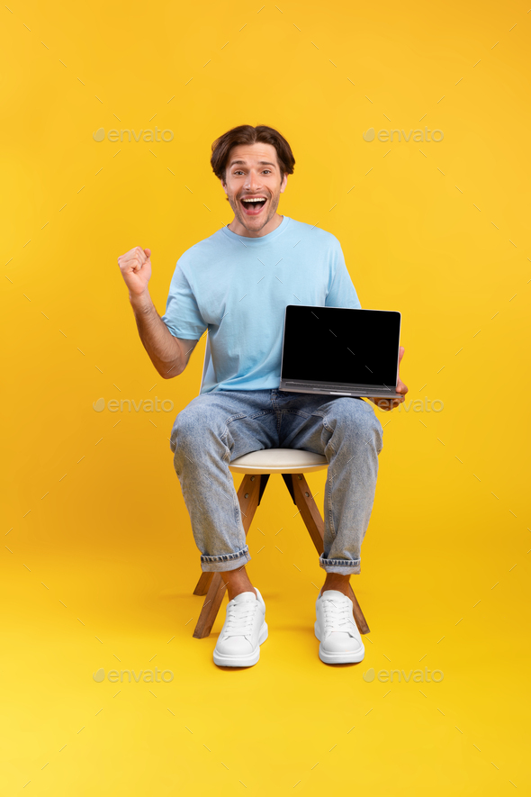 Excited man showing black blank laptop screen screaming yes