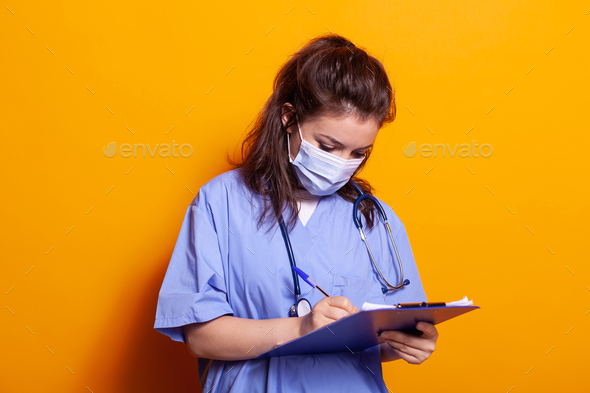 Portrait of nurse wearing face mask and taking notes