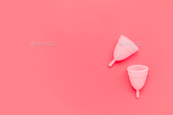Pink menstrual cup on color background, female intimate hygiene period products, top view