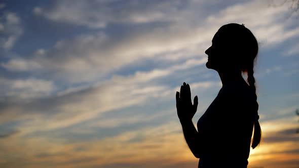 Silhouette of a woman praying with Amazing dramatic sky sunset background. alt