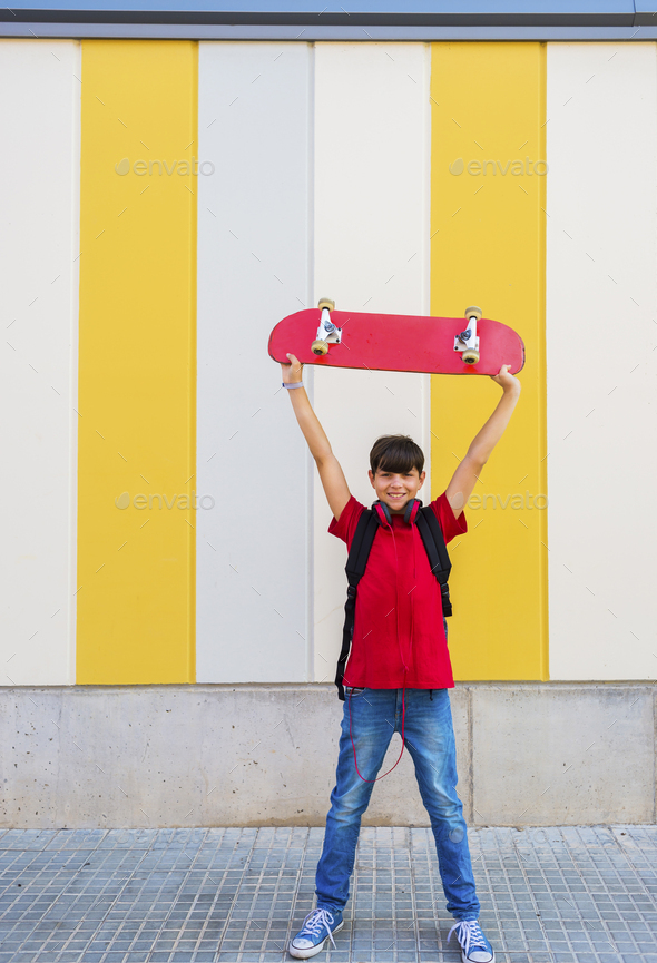 Happy youngster with skateboard above head
