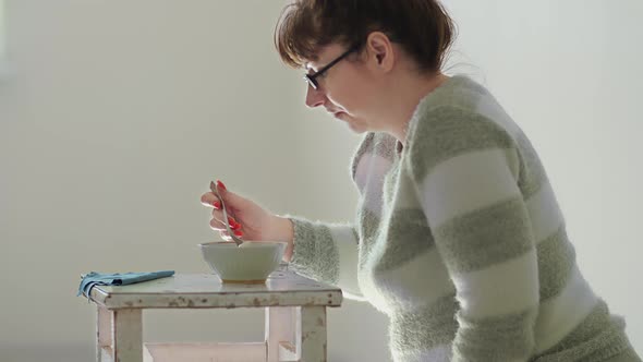 Woman Sitting on the Floor and Eating Noodles on Stools Economic Crisis Cheap Food alt