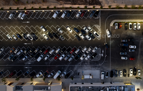 Drone aerial view of parking lots with cars at night. Crowded shopping mall car park