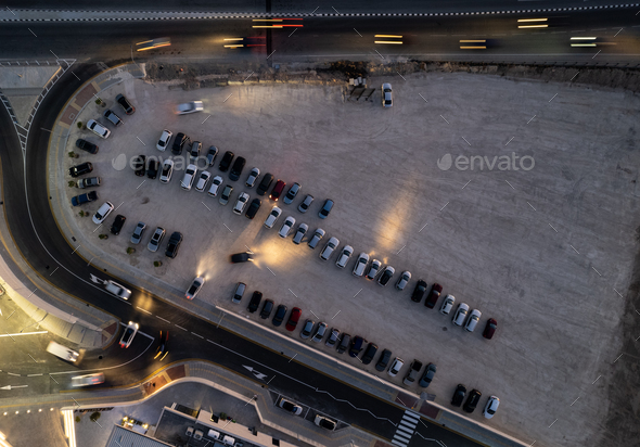 Drone aerial view of parking lots with cars at night. Crowded shopping mall car park