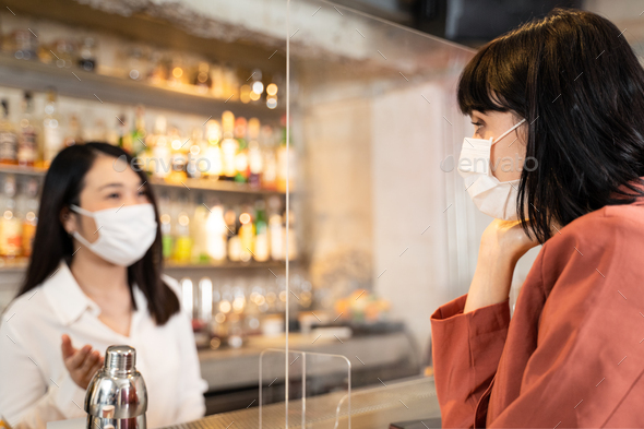 Customer woman dining in restaurant. Waitress with face mask serving food to customer.