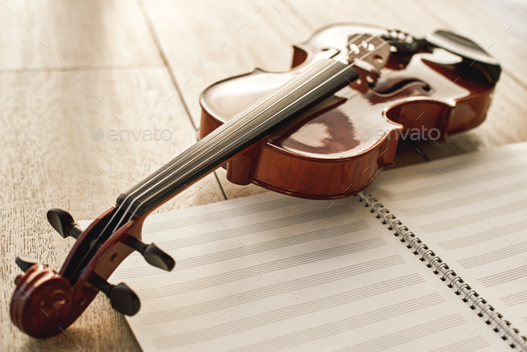 Visual beauty of classical instrument. Close up view of brown beautiful  violin lying on sheets for Stock Photo by friends_stock