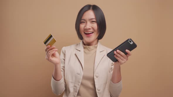 Asian business woman happy smiling and using smart phone and credit card for shopping online