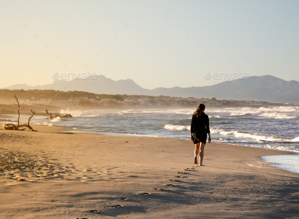 Young woman walking on shore near water - Stock Photo - Images