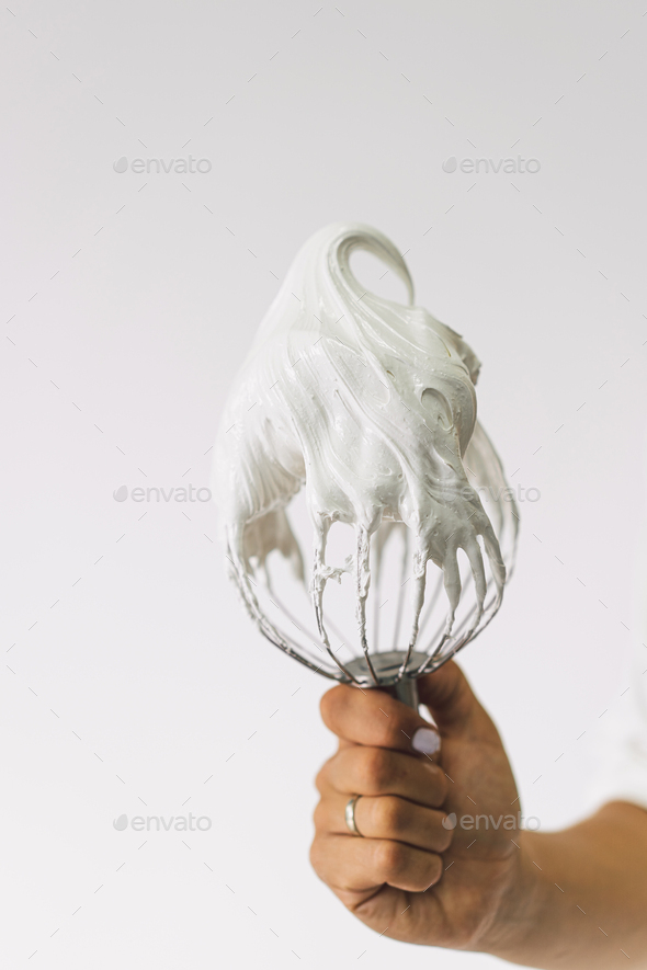 Confectioner girl is preparing a cupcakes. Girl pastry chef with whisk of whipped white proteins