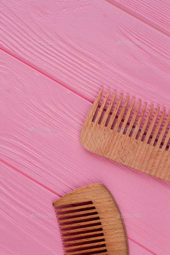 Wooden hair combs on pink background.