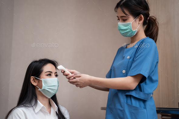 Asian medic nurse measure and check patient temperature from infrared thermometer.