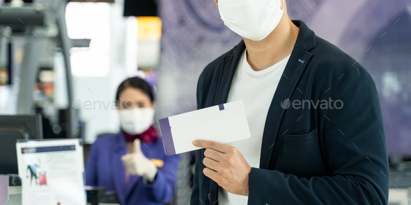 Asian male traveler hold boarding pass ticket at customer check at airline service counter.