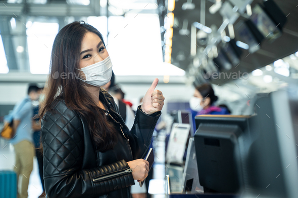Portrait of Asian female traveler holding passport at customer check in of airline service counter