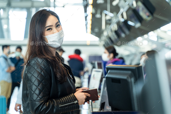 Asian female traveler wear mask holding passport at customer check in of airline service counter