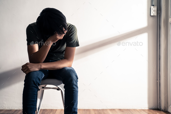 Asian male unemployed worker sit on chair feeling stress that have no job due to crisis.