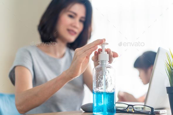 Asian young woman use hand sanitizer gel for clean hands often while work from home