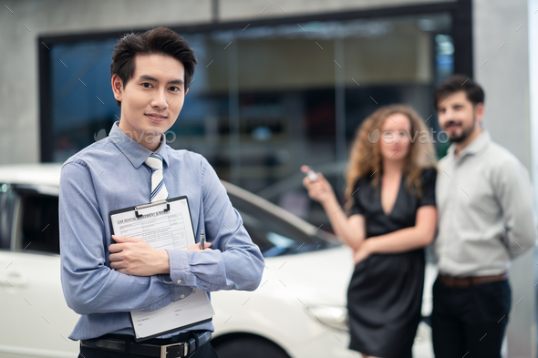 Asian officer male staff stands and holding rental agreement document in front for car rent