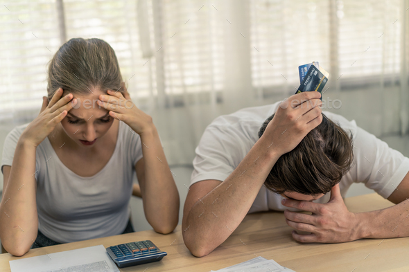 Stressed young Caucasian couples holding credit cards and worry about financial problem