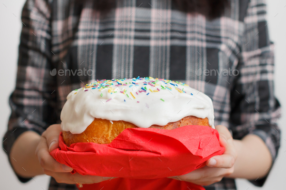 Traditional Easter cake in womans hands. Easter bread with white cream and colorful decoration on