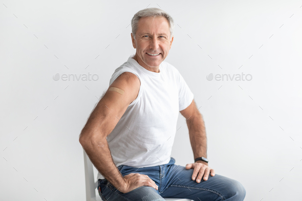 Vaccinated Mature Male Showing Arm With Plaster Over Gray Background - Stock Photo - Images