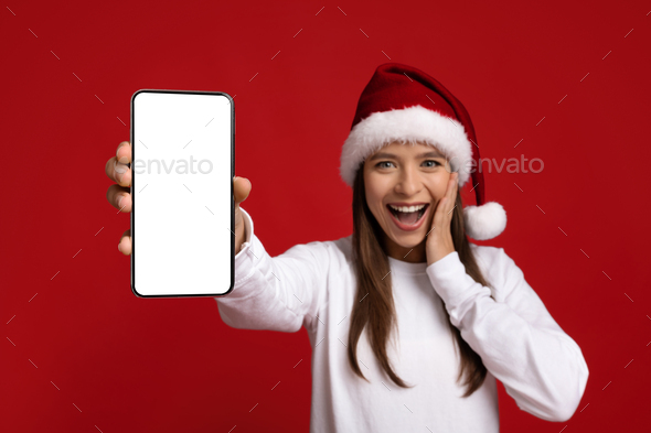 Amazing Offer. Excited Young Lady In Santa Hat Showing Blank Smartphone - Stock Photo - Images
