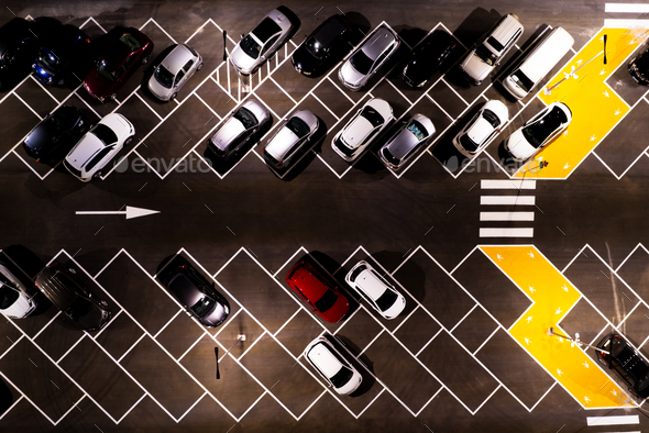 Drone aerial view of parking lots with cars at night. Crowded shopping mall outdoor car park