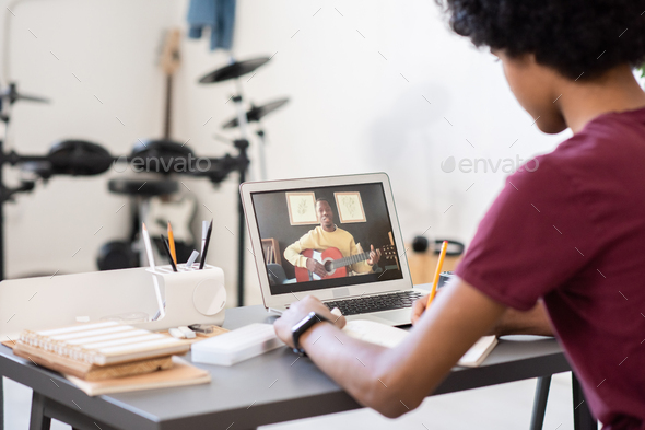 Young blackman with guitar teaching music on laptop screen