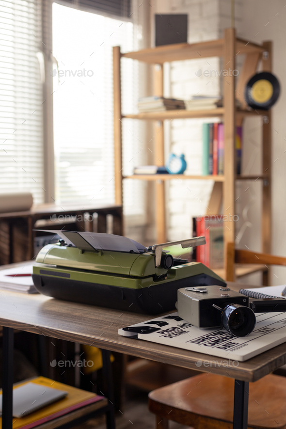 Vintage old film camera and typewriter at wooden desk table