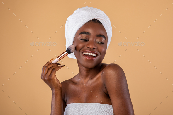 Portrait of happy black woman with makeup brush