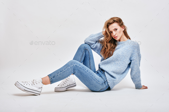 What do you mean Brown-haired, cute girl sitting on the floor, touching her hair with a surprised - Stock Photo - Images